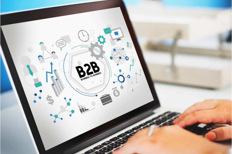 A person works on a laptop showing a graphic of the "B2B Business to Business" concept surrounded by icons