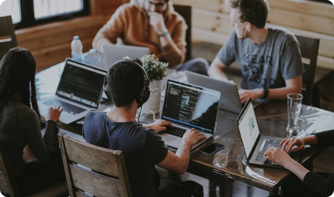A group of young professionals working together on laptops in a collaborative workspace, discussing tech projects and digital tools like how to activate WhatsApp for business communication.